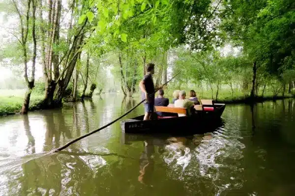 Un guide batelier pousse une barque avec une pigouille dans le Marais poitevin